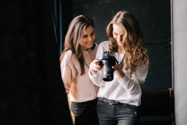 istock Woman photographer with model looking on camera screen in studio. 1248947482