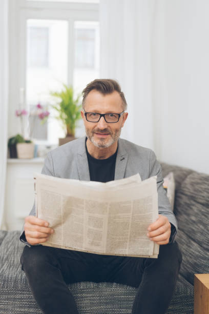 istock Mature metro man reading newspaper in lounge room 1248948271