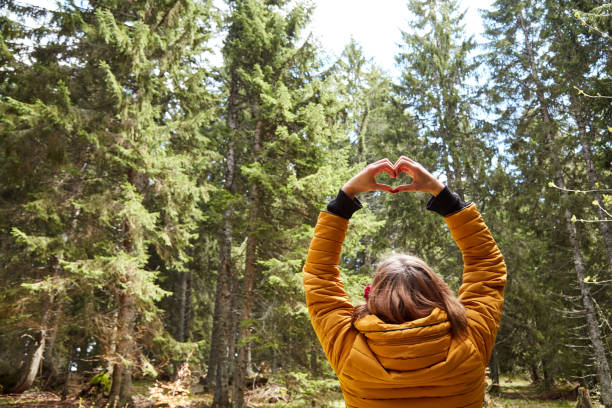 mujer con símbolo en forma de corazón que se sostiene en el aire en el entorno natural. - heart shape loneliness women praying fotografías e imágenes de stock