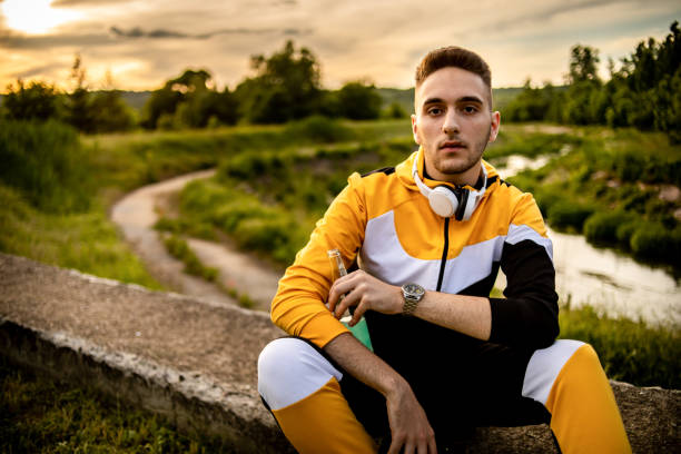 The young man sits in nature and enjoys the sunset