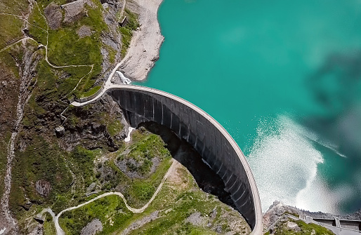 The Zambezi river is dammed here at this wall, with a road border running along the top of it and floodgates in view. People and cars on the wall show the scale of this engineering marvel. Photographed in August 2013.