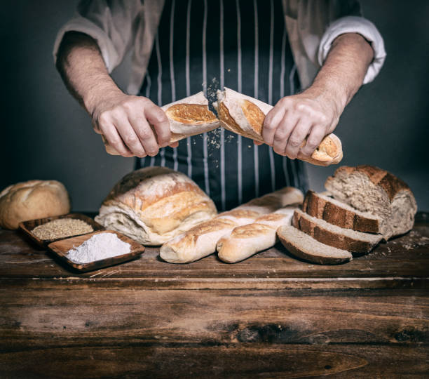 istock Baker breaking baguette in two halves at bakery on wooden table 1248959741