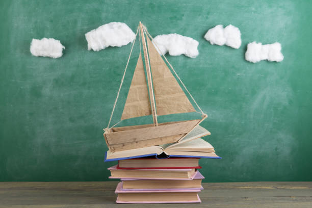 Education is a journey concept, toy boat and books on the chalkboard background, inspiration for a fairy tale stock photo