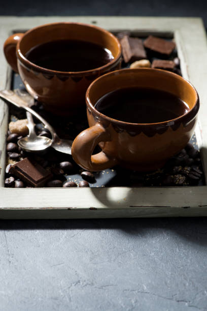 istock fresh black coffee in a cups and chocolate on blackboard, vertical 1248966543