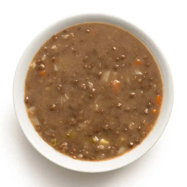 Lentil soup in a white ceramic bowl isolated on white. Top view.