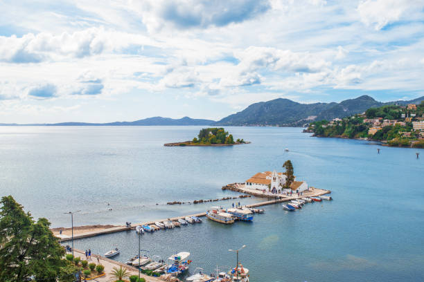 Kerkyra, Corfu Island, Greece - October 4, 2019: Halkiopoulos lagoon with the Vlacherna Monastery and Pontikonisi (means Mouse Island ) in Corfu, Greece, plane in sky. Landscape of Ionian sea beach.