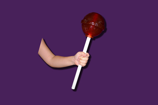 Child hand holds a huge lollipop Chupa Chups