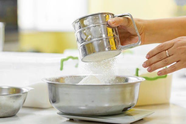 cozinhando cozimento. cozinhe peneira a farinha de perto - cake making mixing eggs - fotografias e filmes do acervo