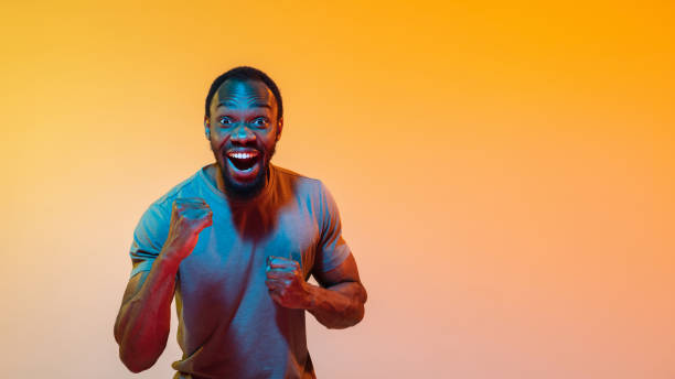 istock African-american man's portrait isolated on gradient orange studio background in neon light 1248978509