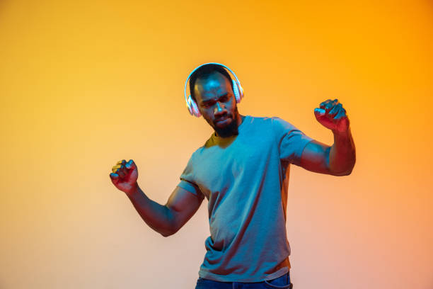 istock African-american man's portrait isolated on gradient orange studio background in neon light 1248978518