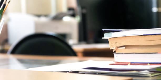 Office desk, panoramic view. Stack of books and papers, printer, stationery