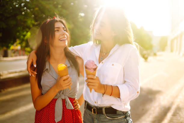 istock Two young female friends having fun and eating ice cream. 1248984229