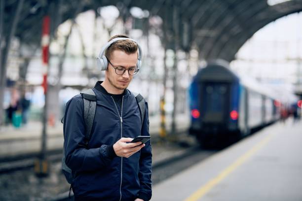 istock Man with headphones using phone at railroad station 1248984725