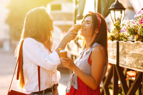 istock Two young female friends having fun and eating ice cream. 1248984762