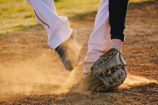 Baseball player on ball field with dust from play at sunset.