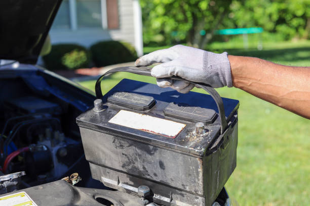 an african-american man taking a car battery out of a truck - car battery imagens e fotografias de stock