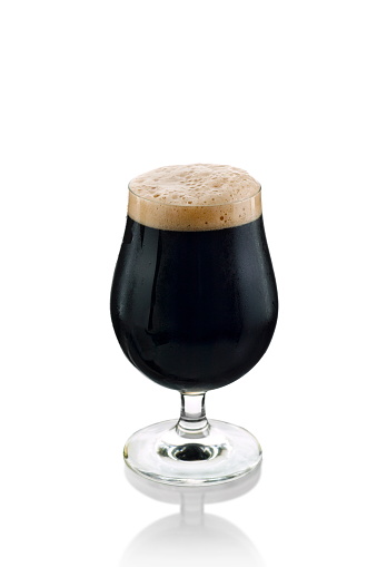 black beer being poured into a specific glass