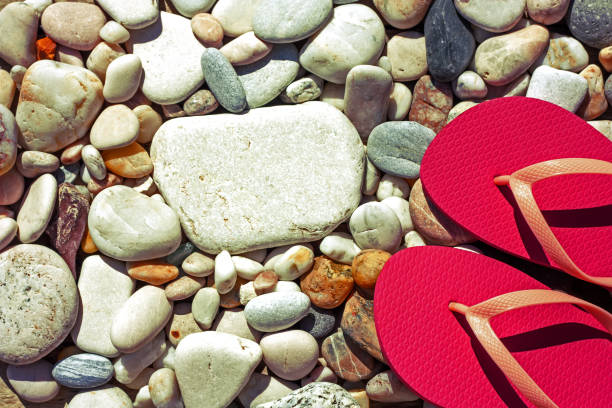 red towel, stones, and beach slippers on pebble beach, sunset