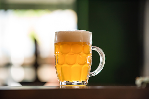 Two glasses of beer on a bar counter.