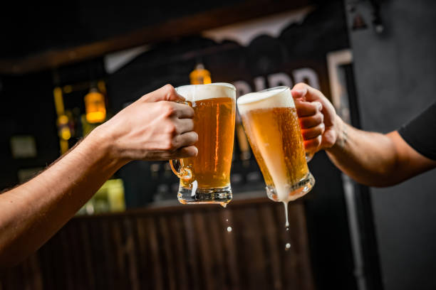 zwei leute toasten mit tassen voller hacken. - beer stock-fotos und bilder