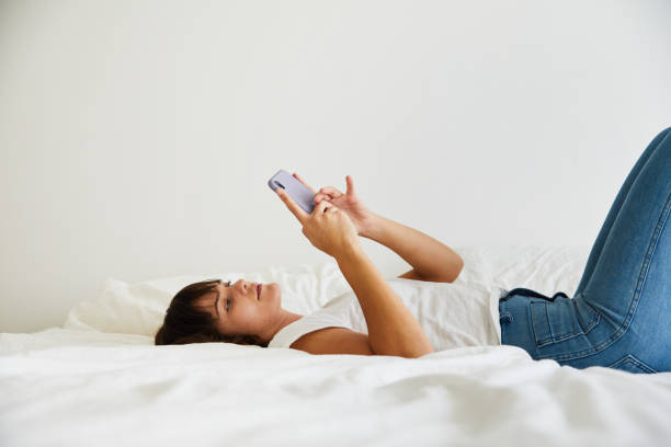istock Young woman lying on her bed and texting on her cellphone 1248996214