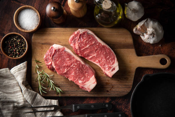 striscia cruda carne bistecca di manzo su tagliere in legno - strip steak steak beef raw foto e immagini stock
