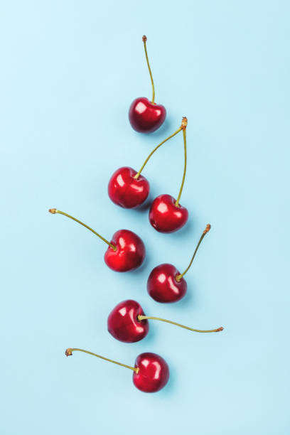 Composition of ripe cherries on a blue background. Composition of ripe cherries on a blue background. Flat lay, top view. vibrant color lifestyles vertical close up stock pictures, royalty-free photos & images