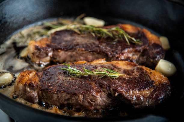 istock cooking new york strip steak on skillet pan 1248998812