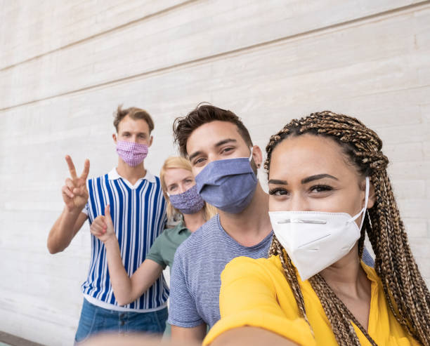 Young people meet and take a selfie - Multiracial friends wearing protective face masks - Focus on the face of the african woman Young people meet and take a selfie - Multiracial friends wearing protective face masks - Focus on the face of the african woman rules photos stock pictures, royalty-free photos & images