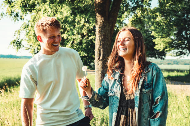 Young Couple Outdoor Fun Blowing Dandelion