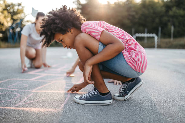 istock Friends drawing hopscotch court using chalk 1249002296