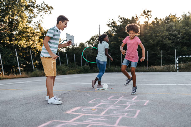 istock Mother holding plastic hoop while children playing hopscotch 1249002343