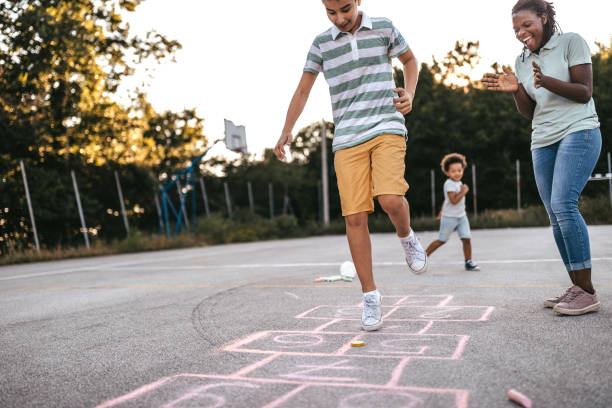 istock Mother encouraging son playing hopscotch 1249002459