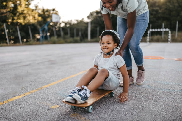istock Mother with daughter riding skateboard on playground 1249002612