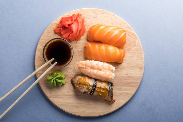 köstliches appetitliches nigiri-sushi-set auf holztellern mit sojasauce und essstäbchen serviert. grauer hintergrund - chopsticks soybean japanese cuisine blue stock-fotos und bilder