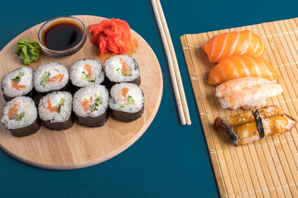 nahaufnahme von frischem sushi und brötchen auf holzbrett serviert - chopsticks soybean japanese cuisine blue stock-fotos und bilder
