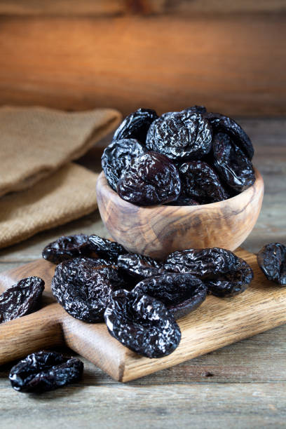 istock Prunes in a bowl on old wooden table. 1249004079