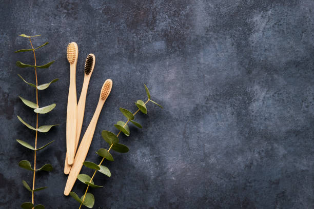 istock Flat lay composition with bamboo toothbrushes and eucalyptus branch on dark grey background. Top view, copy space 1249007296