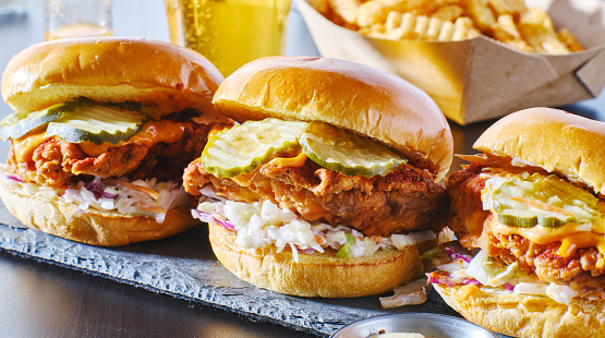 spicy nashville hot chicken sandwich with coleslaw and pickles in a row