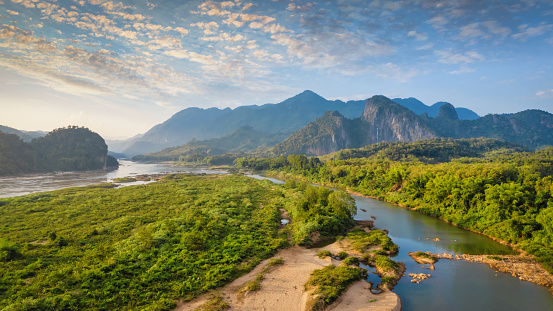 Panorama along the Mekong River in Laos close to Pak Ou - Luang Prabang. Majestic Mekong River surrounded with Karst Rock Formations and tropical Hill Range in late afternoon twilight. Drone Panorama. Mekong River between the city of Luang Prabang and Pak Ou, Mekong River, Luang Prabang, Laos, Southeast Asia