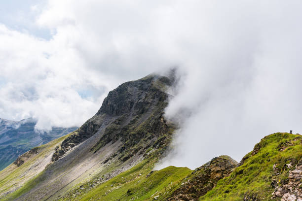 istock Austrian Alps partially covered with clouds on one side and sunshine on the other 1249014349
