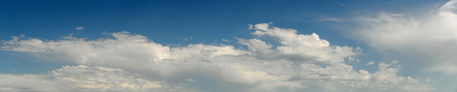 Blue sky background with clouds and sun rays coming out.