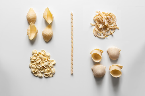 Different types of artisanal Italian pasta. Food knolling, space for copy with easily extendable white background.