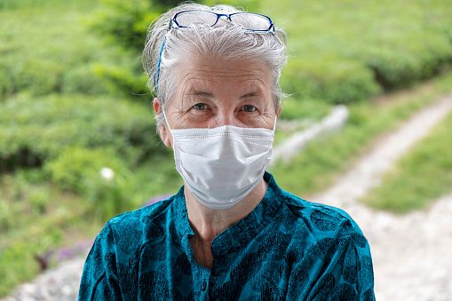 Portrait shot of senior woman wearing medical mask because of coronavirus.