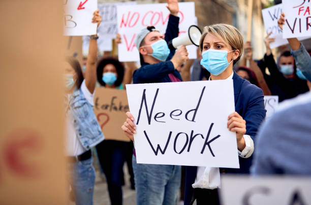 istock Woman wearing protective face mask while holding need work sign on a protest. 1249018687