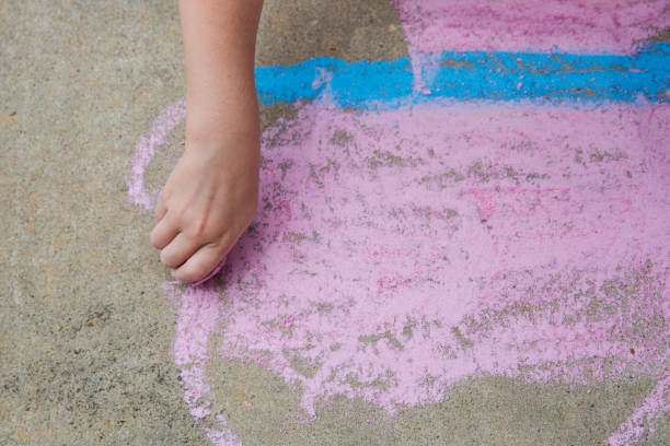 istock Young child using sidewalk chalk to draw a butterfly 1249019201