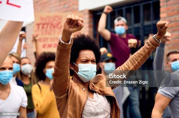 African American Woman Wearing Protective Face Mask While Protesting With Arms Raised On City Streets Stock Photo - Download Image Now