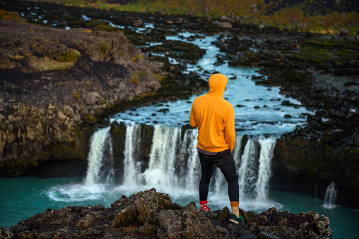 Young hiker standing at the Thjofafoss waterfall located on the river Thjorsa on the east side of the Merkurhraun lava fields in the south of Iceland.