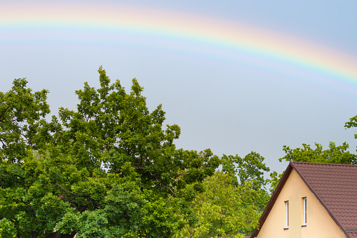 Beautiful rainbow over the roofs, house in summer.