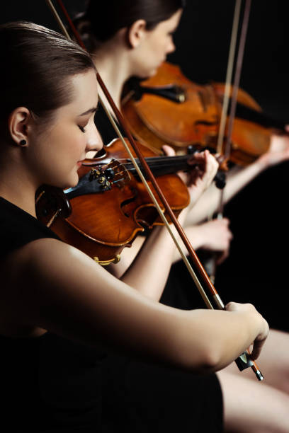istock professional female musicians playing classical music on violins on dark stage, selective focus 1249020932